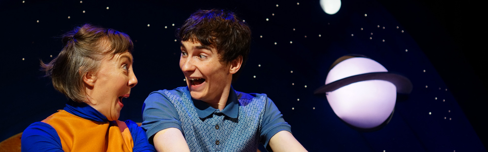 Two performers smiling at each other in space.