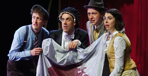 Four actors in period costume holding a blood-stained tablecloth