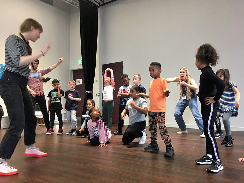 A group of children stroke a pose during Summer School