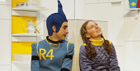 Two characters - a girl and a robot - on stage