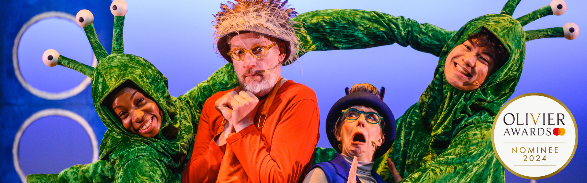 Two actors dressed as Grandfather Smed and Grandmother Smoo from The Smeds and The Smoos. They are trapped between two aliens with long green arms and three eyes on top of their heads. In the background is a blue rocket. In the bottom right hand corner there is an Olivier Award Nominee badge.