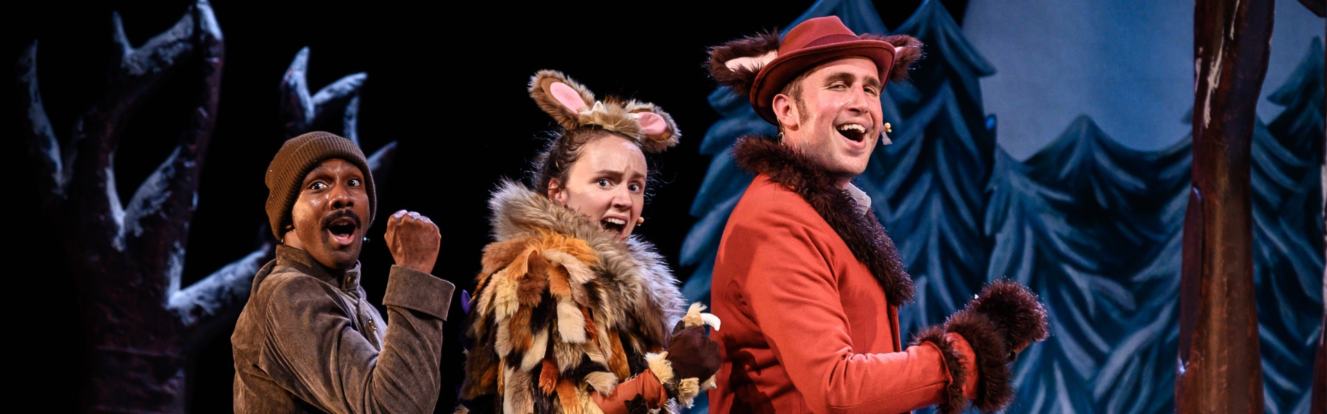 Three actors on stage in a line, ready to dance